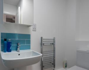 Riverside apartment with views and parking في كينغسبريدج: حمام مع حوض أبيض وبلاط أزرق