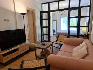 ein Wohnzimmer mit einem Sofa, einem TV und einem Bett in der Unterkunft Aelia luxury apartment with private entrance in Karavomylos