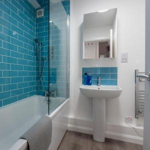a bathroom with a sink and a shower with blue tiles at Riverside apartment with views and parking in Kingsbridge