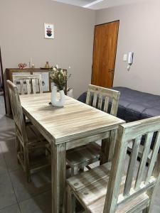 drewniany stół z krzesłami i wazon z kwiatami w obiekcie ALBORES DE UCO w mieście La Consulta