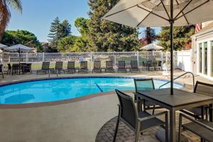 - une table avec un parasol à côté de la piscine dans l'établissement Residence Inn Sunnyvale Silicon Valley I, à Sunnyvale