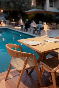 una mesa de madera y sillas junto a una piscina en Anthemion Suites and Villas, en Nauplia