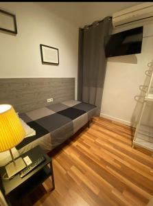 1 dormitorio con 1 cama y 1 mesa con lámpara en SINGLE ROOMS en Madrid