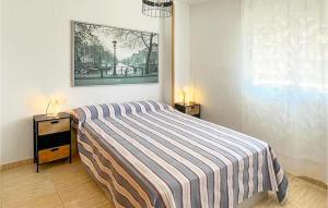 sypialnia z łóżkiem z paskowym kocem i stolikiem nocnym w obiekcie 2 Bedroom Cozy Apartment In Oropesa w mieście Oropesa del Mar