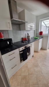 una cocina con armarios blancos y encimeras negras en RTM COMFORTABLE Home, en Basildon