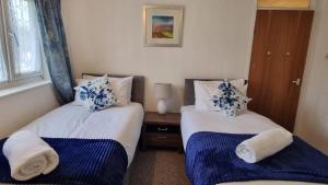RTM COMFORTABLE Home في باسيلدون: غرفة نوم بسريرين مع وسائد زرقاء وبيضاء