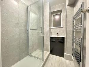 Fabulous 3 bedroom flat sleeps 6 في لندن: حمام مع دش زجاجي ومغسلة