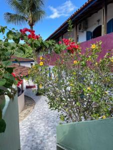 einen Garten mit roten und gelben Blumen neben einem Gebäude in der Unterkunft Villa Di Verona Charm Hotel in Guarujá