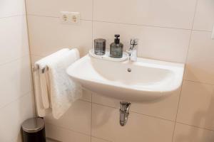 a white sink in a white tiled bathroom at Servus Apartments Neuhaus am Inn in Neuhaus am Inn