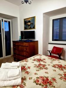 sypialnia z łóżkiem, telewizorem i czerwonym krzesłem w obiekcie Nanninella hh w Sorrento