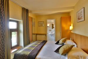 a bedroom with a large bed and a bathroom at Auberge Des Cretes in Falmignoul