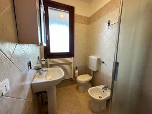 Un baño con lavabo, inodoro y ventana. en Villino a Lido degli Estensi, en Lido degli Estensi