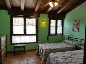 Duas camas num quarto com paredes verdes e janelas em Casa Felisa Pirineo Aragonés em Santa Eulalia de Gállego