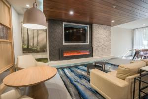a living room with a fireplace and a table and chairs at Fairfield Inn & Suites by Marriott Gainesville I-75 in Gainesville