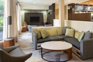 a lobby with a couch and chairs and a table at Courtyard by Marriott Orlando Airport in Orlando