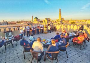a group of people sitting at tables eating food on a roof at HOTEL KALA KHIVA in Khiva