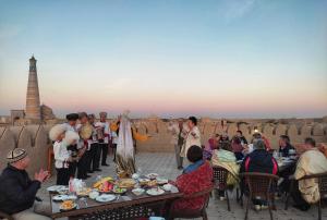 een groep mensen die aan tafels op een dak zitten bij HOTEL KALA KHIVA in Khiva