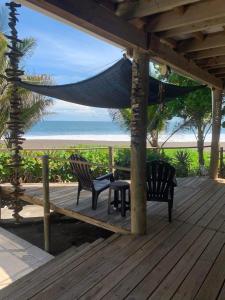 a porch with two chairs and a hammock on the beach at Casa, Cabo Tortugas, Monterrico in Monterrico