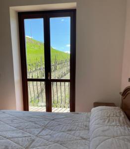 Schlafzimmer mit einem Bett und einem Fenster mit Aussicht in der Unterkunft Spicchio di Langa - casa indipendente tra le vigne e le Alpi in Belvedere Langhe