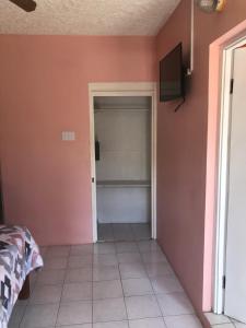 a bedroom with a pink wall and a television at Negril Beachside in Negril