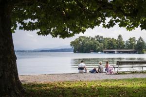 people sitting on a bench near a body of water at Wellness Hotel Aquafit Sursee in Sursee