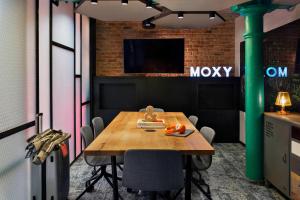 a conference room with a wooden table and a tv at Moxy Warsaw Praga in Warsaw
