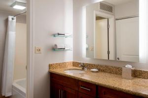 Residence Inn Syracuse Carrier Circle في إيست سيراكيوز: حمام مع حوض ومرآة وحوض استحمام