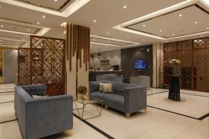 eine Lobby mit 2 Stühlen, einem Tisch und einem TV in der Unterkunft فندق وايت مون للأجنحة الفندقية in Chamis Muschait