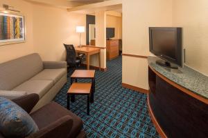 a living room with a couch and a tv in a hotel room at Fairfield Inn & Suites by Marriott Portland North in Portland