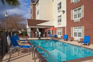 a swimming pool with blue chairs and a building at TownePlace Suites New Orleans Metairie in Harahan