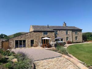 een stenen huis met een patio en een gazon bij Cuthbert Hill Farm in Preston