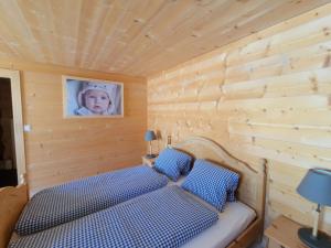 a bed in a wooden room with a picture of a baby at Sonja's Michelshof in Sankt Antönien