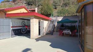 a patio with a table and a green umbrella at Casa Millar. in Huergas y El Millar