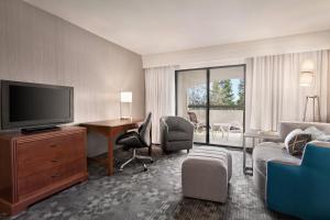 a hotel room with a television and a desk and chairs at Courtyard by Marriott San Jose South/Morgan Hill in Morgan Hill