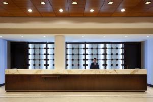 Ein Mann steht vor einem Fenster in einer Lobby. in der Unterkunft Marriott Orlando Airport Lakeside in Orlando