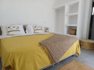 a bedroom with a bed with a yellow blanket and pillows at Alko Apartments in Mikonos