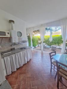 cocina con encimera con cortinas blancas y mesa en La casa di Leo, en Santa Maria Navarrese