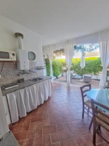 a kitchen with a counter with white curtains and a table at La casa di Leo in Santa Maria Navarrese