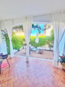 een woonkamer met witte gordijnen en een patio bij La casa di Leo in Santa Maria Navarrese