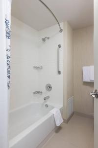Residence Inn Minneapolis Downtown/City Center في مينيابوليس: حمام أبيض مع حوض استحمام ودش
