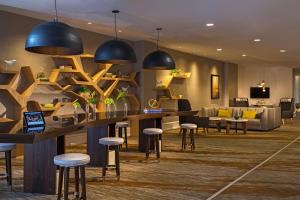 a lobby with a bar with stools and a couch at Renaissance Raleigh North Hills Hotel in Raleigh