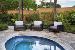 a pool with four chairs and a table and a table and chairsitures at Courtyard by Marriott Maui Kahului Airport in Kahului