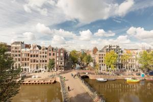 un pont sur une rivière dans une ville avec des bâtiments dans l'établissement The Red Ox - Super Central Canal View Rooms, à Amsterdam