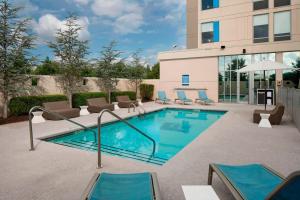 una piscina con sedie a sdraio accanto a un edificio di Aloft Hotel Rogers Bentonville a Rogers