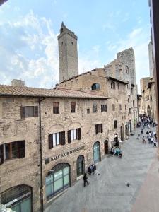 un gran edificio de ladrillo con una torre en el fondo en APPARTAMENTO CISTERNA 33, en San Gimignano