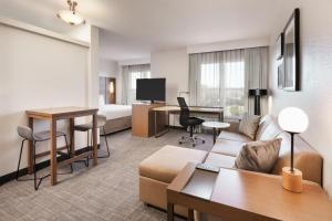a hotel room with a couch and a bed and a desk at Residence Inn by Marriott Daytona Beach Speedway/Airport in Daytona Beach