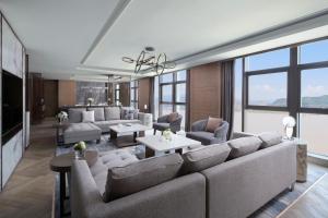 a living room with a large couch and tables and windows at Wenzhou Marriott Hotel in Wenzhou