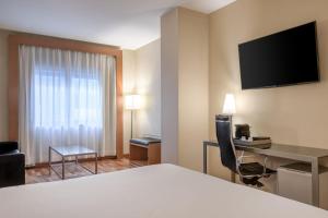 マドリードにあるAC ホテル アラバカのベッド、デスク、テレビが備わるホテルルームです。