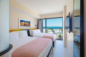 2 łóżka w pokoju hotelowym z widokiem na ocean w obiekcie Moxy Miami South Beach w Miami Beach