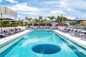 ein Pool mit Stühlen und Sonnenschirmen auf einem Gebäude in der Unterkunft Moxy Miami South Beach in Miami Beach
